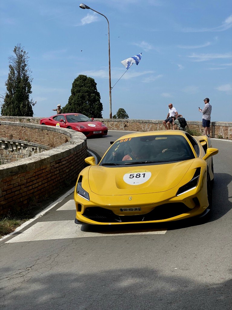 Yellow Ferrari on a Mille Miglia bend with village rooftops beyond - OHH! Italy