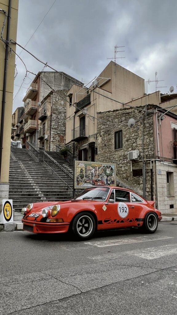 Red Porsche Carrera RS on a Sicilian village street with Targa Florio mural - OHH! Italy private journey