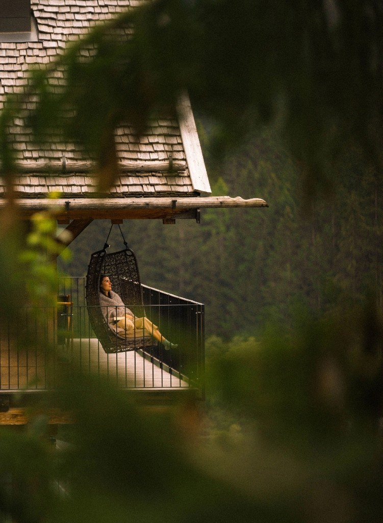 Hanging chair on a chalet balcony overlooking the forest