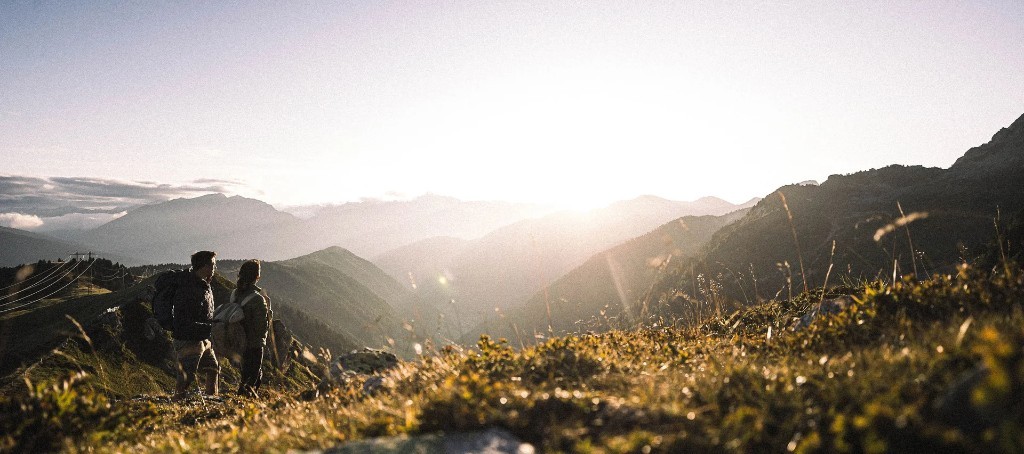 Hikers on an alpine ridge at golden hour · Racines