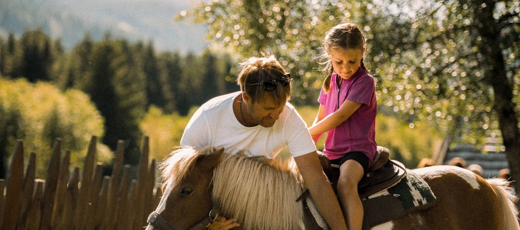 Child on a pony with parent · Alpura Retreat summer experience