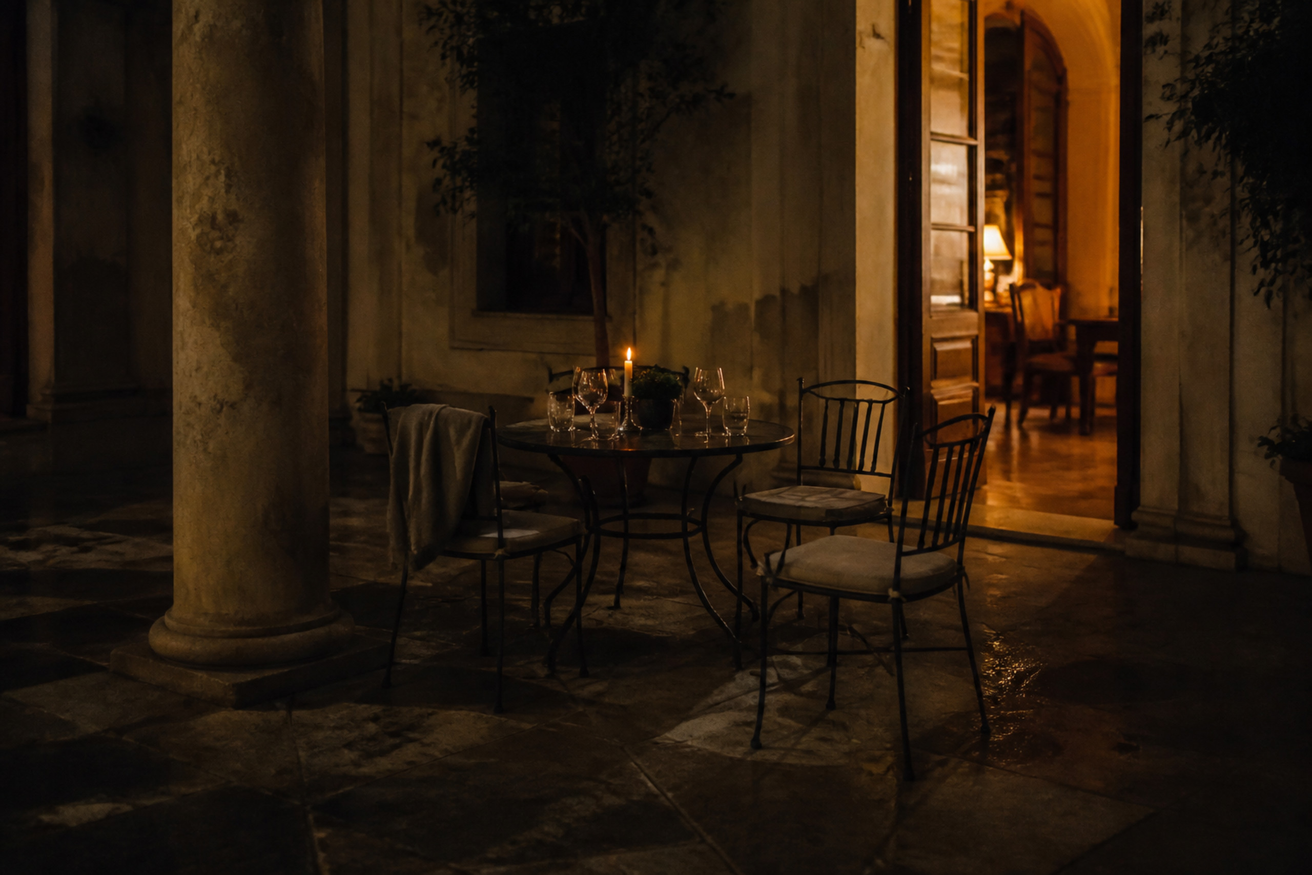 Quiet Italian hotel courtyard after dinner with chairs, glasses and candlelight
