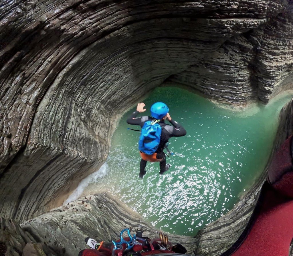 Canyoner mid-jump into a turquoise pool between narrow rock walls, OHH! ITALY Journal