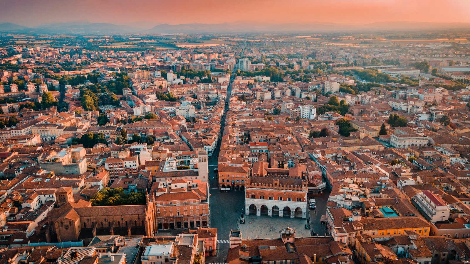Piacenza from above: Piazza Cavalli, the Gothic palace, terracotta roofs running toward the plain.