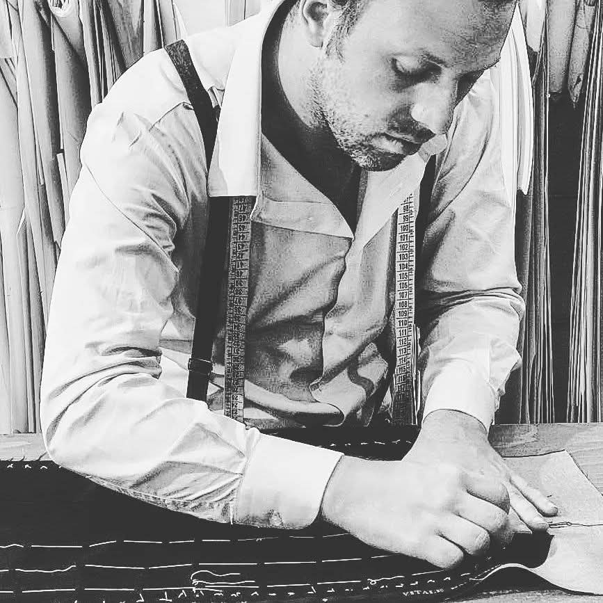 Francesco Caruso marking cloth at the workbench — chalk lines on bespoke fabric