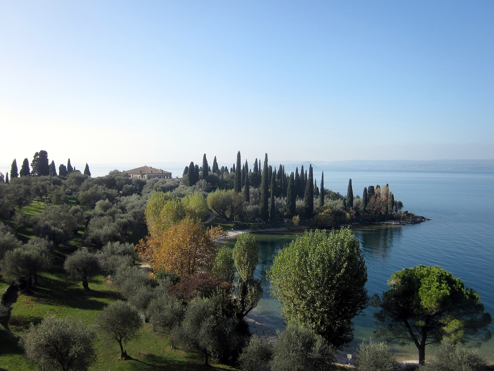 Punta San Vigilio as a wooded headland of cypress and olive, with water on three sides